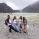 A group of travelers posing by the turquoise crater lake at Kawah Putih, Ciwidey, West Java, surrounded by misty hills.