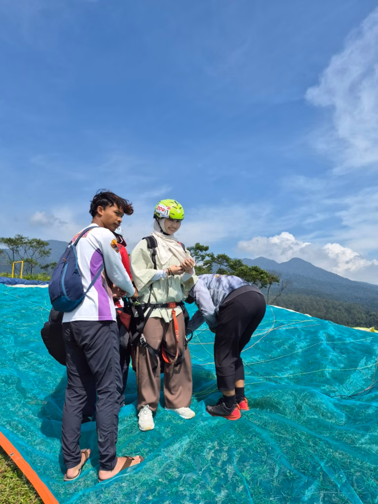 Tourist preparing for tandem paragliding in Lembang Bandung with instructors and mountain scenery