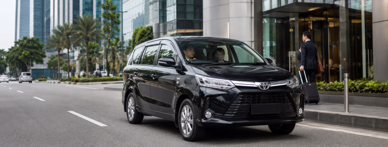 Private driver service for a business trip in Jakarta with a car, driver, and business passenger near a modern office building.